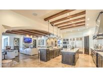 Spacious kitchen with wooden beams, double islands, stainless appliances, and open floor plan to living room at 13074 E Saddlehorn Trl, Scottsdale, AZ 85259