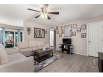 Bright living room with a ceiling fan, wood laminate floors, white couch, and stylish decor at 1531 W Campo Bello Dr, Phoenix, AZ 85023