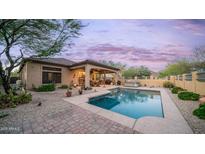 Inviting backyard oasis featuring a sparkling pool, covered patio, and desert landscaping, perfect for relaxation at 9037 E Indigo St, Mesa, AZ 85207