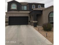Two-story home featuring a dark gray stucco exterior, brown accents, and a paved driveway leading to an attached two-car garage at 4972 S 238Th Ln, Buckeye, AZ 85326