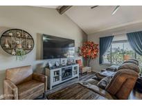 Comfortable living room features a vaulted ceiling, stylish furniture, and a decorative fireplace with a large screen TV at 6433 E University Dr, Mesa, AZ 85205