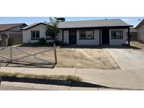 Traditional single-story home with dark trim, covered porch, and low fence at 1818 N 63Rd Ave, Phoenix, AZ 85035