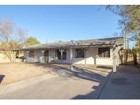 Single story house with a carport, painted white with gray trim and a gravel yard at 3418 W Roma Ave, Phoenix, AZ 85017