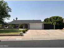 Charming single-story home with a well-manicured lawn, mature trees, and a spacious two-car garage at 7413 W Columbine Dr, Peoria, AZ 85381