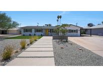 Charming single-story home featuring a manicured lawn, elegant walkway, and a welcoming yellow front door at 2809 E Shangri La Rd, Phoenix, AZ 85028