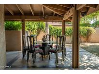 Covered outdoor dining area with a glass table, stylish chairs, and lush landscaping creates an inviting space at 4525 N 66Th St # 112, Scottsdale, AZ 85251