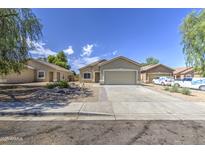 A tan single-Gathering home showcases its spacious driveway and xeriscaped front yard under a clear, blue sky at 15336 W Maui Ln, Surprise, AZ 85379
