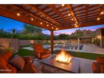 Inviting backyard with a fire pit, pool, jacuzzi, outdoor kitchen, and lush landscaping perfect for relaxing at 4518 E Solano Dr, Phoenix, AZ 85018