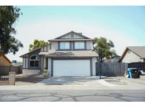 Traditional two-story home featuring a two-car garage, manicured lawn, and a basketball hoop over the driveway at 1632 E Saint Charles Ave, Phoenix, AZ 85042