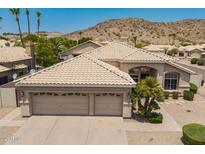 Beige single-story home featuring a three-car garage and desert landscaping at 2550 E Amberwood Dr, Phoenix, AZ 85048