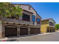 Three-story condo exterior with multiple garages, beige stucco, and flowering tree in the foreground at 2725 E Mine Creek Rd # 1149, Phoenix, AZ 85024