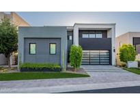 Modern home showcasing a sleek design with a glass garage door and manicured landscaping at 4544 N Evans Dr, Scottsdale, AZ 85251