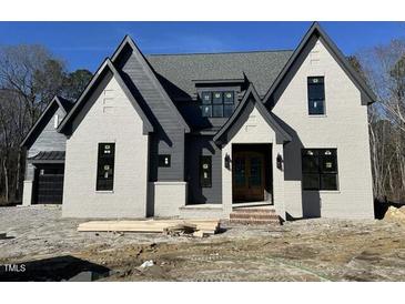 Striking two-story new construction home with gray brick and complementary trim details under a clear blue sky at 3812 Peaceful Creek Trl, Zebulon, NC 27597