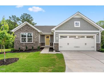 Charming home with a two-car garage, stone accents, manicured lawn and a bright yellow front door at 164 Clove Hitch Ln, Fuquay Varina, NC 27526