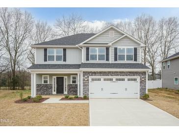 Charming two-story home boasts stone accents, a two-car garage, and a well-manicured front lawn at 138 New Twin Branch Ct, Smithfield, NC 27577