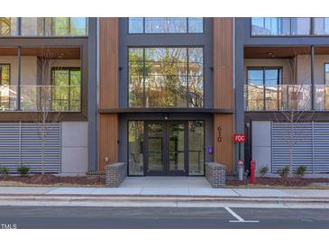 Modern building entrance with glass doors and wood accents, complemented by manicured landscaping at 600 N Roxboro St # 43, Durham, NC 27701