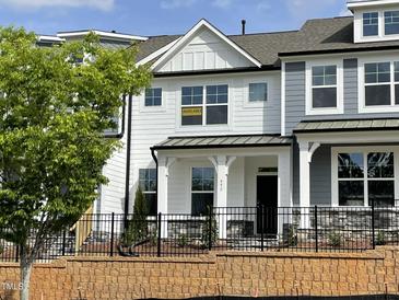 Charming new construction two-story home featuring black wrought iron fence, neutral paint colors, and manicured landscaping at 492 Traditions Grande Blvd # 26, Wake Forest, NC 27587