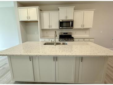 Bright kitchen featuring white cabinets, stainless appliances, and a large island with a sink at 492 Traditions Grande Blvd # 26, Wake Forest, NC 27587