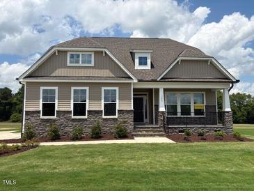 Charming single-Gathering home featuring stone accents, well-manicured lawn, and inviting front porch at 103 Sage Ln # 009, Four Oaks, NC 27524