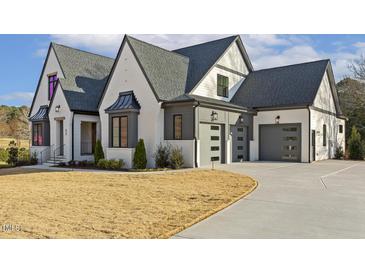 Stunning two-story home with a modern design, gray roof, white painted brick, and three-car garage at 43 Laurel Knoll Dr, Pittsboro, NC 27312