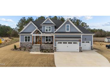 Beautiful two-story home featuring a gray exterior, stone accents, and a three-car garage at 262 Hook Dr # 12, Fuquay Varina, NC 27526