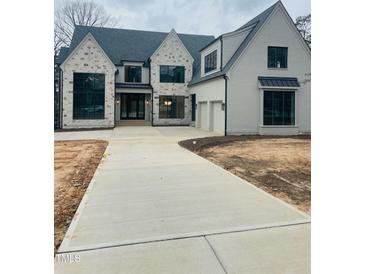 Stunning new two-story home with stone and painted brick, a paved driveway, and an attached two-car garage at 2227 Wheeler Rd, Raleigh, NC 27607