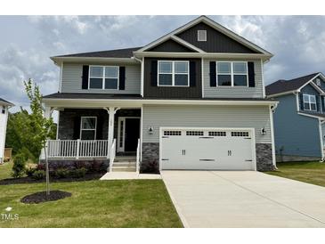Two-story home featuring light gray siding, a two-car garage, and a welcoming front porch at 152 Southern Estates Dr, Sanford, NC 27330