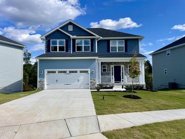 Charming two-story home features a covered front porch and a two-car garage with blue siding at 303 Bishop Ln, Sanford, NC 27330