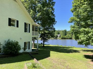 A white brick home with a gorgeous green lawn overlooking the serene lake view at 3309 Westcott Cir, Sanford, NC 27330