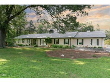 Charming brick ranch home featuring mature trees, lush lawn, and well-manicured landscaping at 11 Pine Forest Dr, Siler City, NC 27344