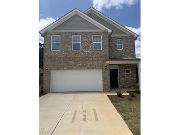Charming brick two-story home features a large garage and well-manicured front yard at 401 Winding Creek Dr, Lillington, NC 27546