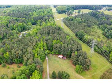 Sprawling wooded acreage features a rustic barn and utility lines in a pastoral setting at 2723 New Sharon Church Rd, Hillsborough, NC 27278
