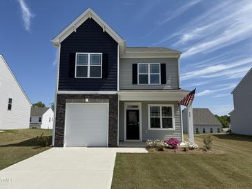 Charming two-story home featuring a stone accent, garage, and manicured lawn with an American flag at 32 Furley St., Homesite 53, Sanford, NC 27330