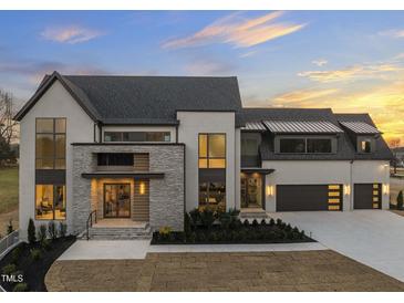 Stunning modern home boasts a brick and stone exterior, large windows, manicured landscaping, and a multi-car garage at 9009 Meadow Pointe Ct, Wake Forest, NC 27587