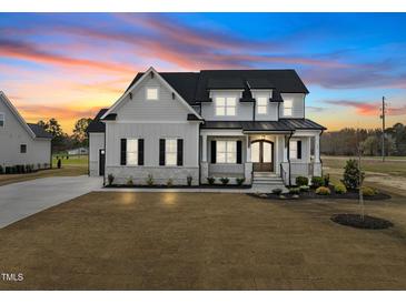 Beautiful two-story home showcasing elegant architectural details and a well-manicured lawn at sunset at 110 Summerlin Dr, Clayton, NC 27527