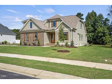 Charming home featuring a beautifully landscaped lawn and a mix of stone and siding exterior at 112 Lambert Ln, Fuquay Varina, NC 27526
