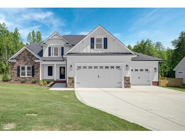 Two-story house with stone and white siding, three-car garage, and manicured lawn at 21 Walnut Hall Ct, Selma, NC 27576