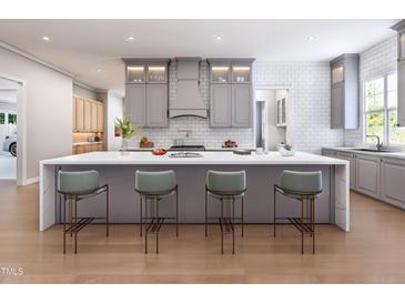 Kitchen featuring gray cabinets, a large white island with seating, and hardwood floors throughout the space at 154 Colonial Trail Ct, Pittsboro, NC 27312