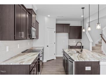 Modern kitchen with dark cabinets, granite countertops, and stainless steel appliances at 176 Van Winkle St, Lillington, NC 27546