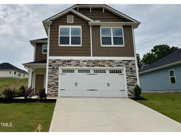 Two-story home with stone accents and a large white two car garage door and concrete driveway at 316 Bishop Ln, Sanford, NC 27330