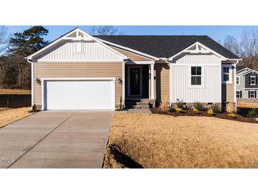 Two-story house with beige siding, white accents, and a two-car garage at 411 Fast Pitch Ln, Four Oaks, NC 27524