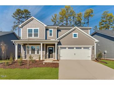 Beautiful two-story home featuring a two-car garage, manicured lawn, and a covered front porch at 736 Heathered Farm Way, Apex, NC 27523