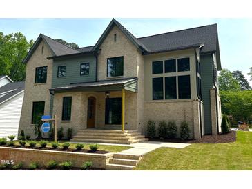 New construction home boasts a brick and siding exterior with a covered porch and manicured lawn at 1000 Marilyn Dr, Raleigh, NC 27607