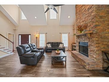 Bright living room features a stone fireplace, hardwood floors, and comfortable black leather furniture at 2674 Stanton Hill Rd, Cameron, NC 28326