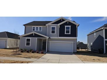 Two-story home with gray and navy siding, a white garage door, and landscaping at 115 Shooting Star Trl, Youngsville, NC 27596