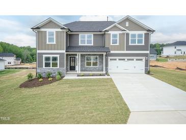 Charming two-story home with a well-manicured lawn and a two-car garage showcasing its appealing curb appeal at 136 Newport Lndg, Garner, NC 27529