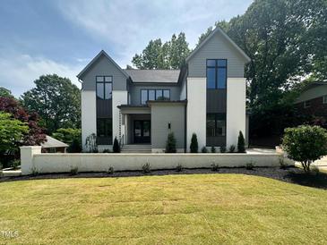 Striking two-story home featuring a manicured lawn, modern design, and professionally landscaped yard at 5208 Knollwood Rd, Raleigh, NC 27609