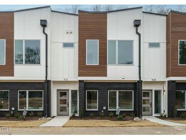 Modern townhome exterior featuring a brick facade, wood and white siding, and contemporary design at 1533 Urban Trace Ln, Raleigh, NC 27608