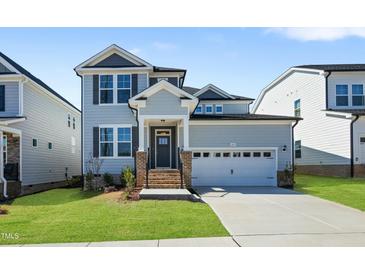 Charming two-story home with a gray exterior, complemented by well-manicured lawn and a two-car garage at 413 Edison Rail Ln, Knightdale, NC 27545