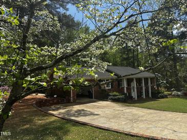Charming brick home featuring a well-manicured lawn and driveway framed by a beautiful dogwood tree at 184 Pine E St, Lillington, NC 27546